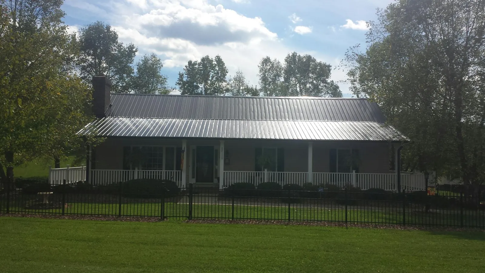 Gray metal roof on a brick ranch with a full width front porch — Gutter Guard Installation work by our crew in Olyphant